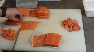 Yetenekli ellerde taze somon mükemmel porsiyonlar halinde dilimlenir. Şef somonu dikkatlice keser ve her parçanın somonun zengin rengini ve hassasiyetini ön plana çıkarır..