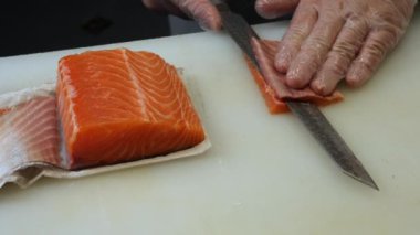 Özel bir bıçak taze somon balığının içinden süzülürken şef daha da çok dilimler oluşturuyor. Somon balığının hassas dokusu, somonun ustalıkla hazırlanmış her kesimiyle sergilenir..