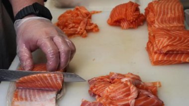 Japon mutfağının ustası özel bir bıçakla taze somonu ustalıkla dilimliyor. Keskin hareketler somon balığının hassas dokusunu gösteren her bir parça somon balığının eşit bir şekilde kesilmesini sağlar..