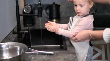 Anne, musluğu açarken bebek kızların kazak kollarını nazikçe düzeltir ve onu akan suyla ellerini yıkamaya hazırlar. Bebek kızlar merak eder, bu anı her gün bir ayin haline getirir..