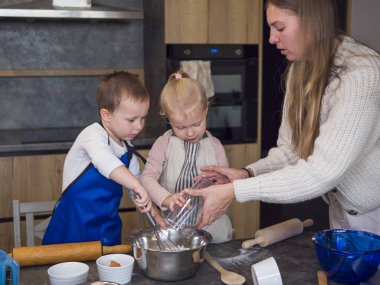 Anne ve çocukları, çok genç bir aşçı olan Hamur Pişirme Konsepti 'ni, rahat ve neşeli bir ortam oluştururken, birbirlerine bağlanıp büyüyen çağdaş bir mutfakta neşeyle kurabiye hamuru hazırlıyorlar.