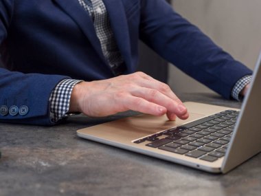 Mavi ceketli adam modern ofiste dizüstü bilgisayarda çalışıyor. Odaklanma ve internette arama yapıyor. Diz üstü bilgisayar şık bir masada oturuyor, insan laptopta verimli görevler yaparken verimliliği vurguluyor.. 