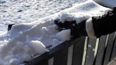 Eldiven takan kadın, karları tahta korkuluklardan temizler. Huzurlu bir ortamda kardan kurtulur. Kar yavaşça yığılır, sakin bir kış gününün özünü yakalar.
