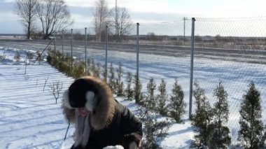 Kış eğlencesi canlanır. Sıcak giysiler içinde genç bir kadın neşeyle havaya kar fırlatır. Kış cazibesiyle dolu, karlı bir günün güzelliğini kucaklar.. 