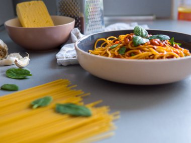 Fesleğen yapraklı domates sosuyla kaplı Balanesi makarnası çiğ makarna, peynir, sarımsak ve rendeyle kaplı tabakta oturur. Balanesi makarna sunumu lezzeti artırır.