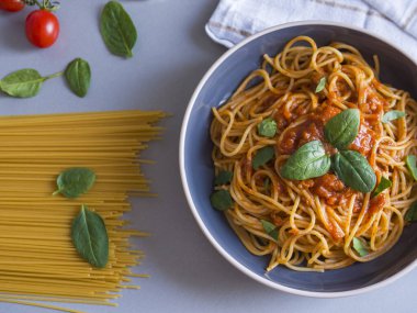 Domates soslu ve fesleğen yapraklarıyla süslenmiş, çiğ spagetti, kiraz domatesleri ve fesleğen yapraklarıyla servis edilmiş Balanesi makarnası.