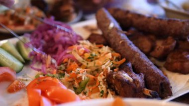 Lula kebabı, ızgara kıymanın popüler bir ortadoğu yemeği, rengarenk domates salatası, salatalık ve turşulu kırmızı lahana ile servis ediliyor, bir şef tarafından bir tabakta düzenleniyor.