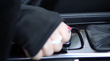 Kadın sürücü modern lüks arabayı çalıştırıp gelişmiş otomotiv teknolojisini ön plana çıkarırken, döner ateşleme düğmesi sorunsuzca dönüyor. Döner ateşleme anahtarı sürüş deneyimini arttırır