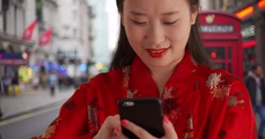 Londra 'da mesajları okumak için akıllı telefon kullanan mutlu Asyalı milenyumu. Avrupa 'da geleneksel moda giyinen sevimli genç bir Çinli kadın. 4k