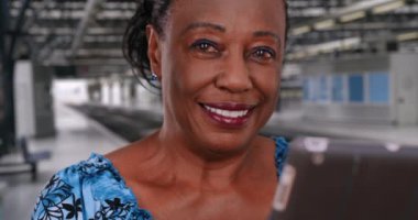 Metro istasyonunda dijital tablet kullanan yaşlı zenci kadının portresi. Afrika kökenli Amerikalı kadın tren beklerken teknoloji kullanıyor. 4k