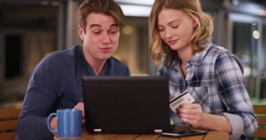 Çekici genç çift bilgisayarla online alışveriş yapıyor. Beyaz erkek ve kadın kredi kartıyla online alışveriş yapıyorlar. 4k