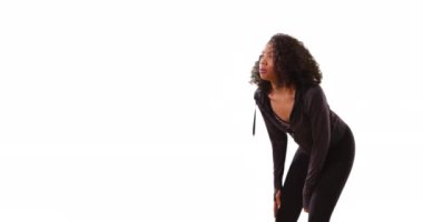 Güzel bir Afro-Amerikan kadın koşuya ara veriyor, beyaz arka planda telif uzayı ile bacaklarını esnetiyor. Stüdyodaki antremandan sonra fotokopi çeken bayan koşucu. 4k