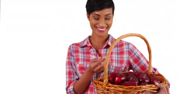 陽気アフリカ系アメリカ人女性有機果物のバスケットを保持し 白い背景にカメラで笑顔 スタジオの片手に赤りんごを投げる若い黒人女性のクローズアップ — ストック動画