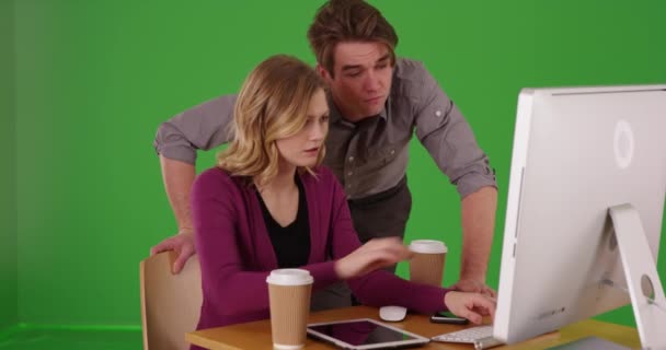 年轻的商人在女性同事在桌面上的绿色屏幕上工作时对她进行监督 绿色供键入或合成 — 图库视频影像