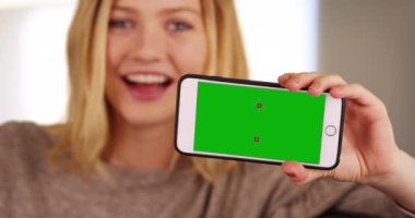 Chroma anahtarıyla cep telefonunu gösteren genç bir kadının portresi. Milenyum kızının elinde kameranın yeşil ekran krom anahtarıyla akıllı telefon tutmasına yakın çekim. 4k