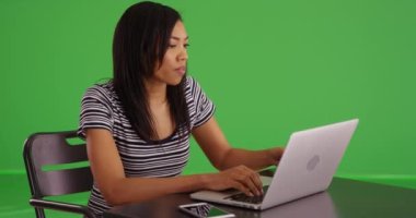 Afro-Amerikalı bir kadın dizüstü bilgisayarda yazarken ve kahve içerken akıllı telefondan mesaj atıyor. Siyahi bir kadın çayını yudumluyor sonra bilgisayarını kullanıyor ve yeşil ekranda telefonla mesajlaşıyor. 4k yeşil ekran
