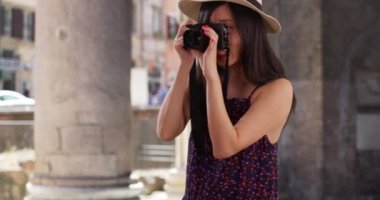 20 'li yaşlarındaki mutlu genç bayan turist İtalya' da DSR kamerasıyla fotoğraf çekiyor. Roma mimarisinin önünde fotoğraf çekmek için fotoğraf makinesi kullanan bin yıllık fotoğrafçıya yakın çekim. 4k