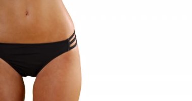 Genç beyaz kız siyah bir bikiniyle boş bir arkaplanda poz veriyor. Beyaz arka planda siyah mayo giymiş bin yıllık beyaz bir kadının orta kesimi. 4k