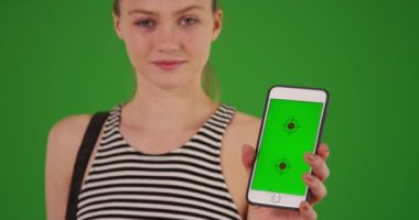 Yeşil ekranda yeşil ekran görüntülü cep telefonu tutan genç bir kızın güzel portresi. Anahtar ya da birleşik olmak üzere yeşil ekranda.