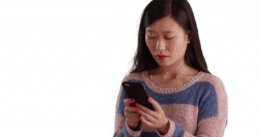 Güzel bir milenyum kadını, izole edilmiş beyaz arka plandaki kısa mesaja cevap vermek için akıllı telefon aygıtı kullanıyor. Asyalı genç bir kadının cep telefonuyla metin göndermesine yakın çekim. 4k