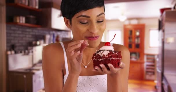 Close Atraente Fêmea Preta Degustação Cupcake Geada Dentro Cozinha Sorrindo — Vídeo de Stock
