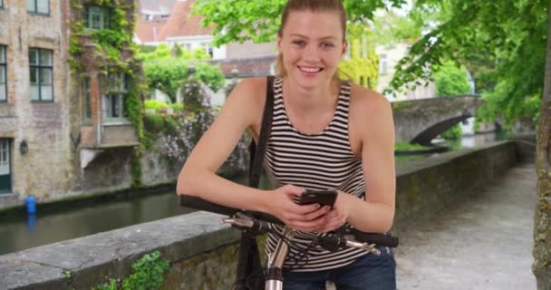 Uśmiechnięty Portret Białej Dziewczyny Brugii Radosna Kobieta Rowerem Smartfonem Uśmiechnięta — Wideo stockowe