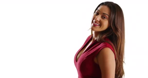 色彩艳丽的拉丁女性穿着性感的红色衣服在白色背景的相机前转过身微笑 一个有着棕色长发的女人在有复制空间的工作室里对着相机笑的画像 — 图库视频影像