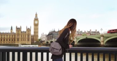 Londra 'da beyaz bir kadın akıllı telefondan harita kullanıyor. Thames nehrinin kıyısında kaybolmuş bir turist cep telefonuyla yön tarif ediyor. 4k