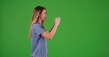 Yeşil ekranda fotoğraf çeken çekici milenyum kızının profili. Anahtar ya da birleşik olmak üzere yeşil ekranda.