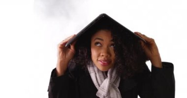 Telif uzayı olan beyaz arka planda dizüstü bilgisayarı olan çılgın yağmurdan korunan tahriş olmuş siyah kadın. Güzel Afrikalı Amerikalı kadın bilgisayarın altında stüdyodaki havadan korunuyor. 4k