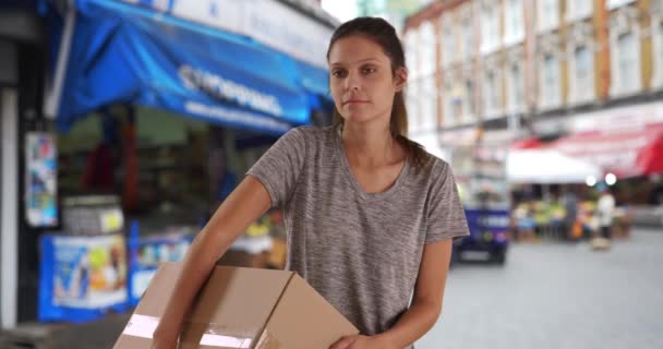 英国的一位忧郁的年轻女子带着装运箱走在街上 随手拿着包裹送递的女性肖像 — 图库视频影像