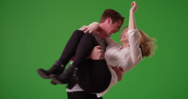 笑着带着顽皮的男人抱着女朋友 在绿色的屏幕上旋转着她 绿色供键入或合成 — 图库视频影像