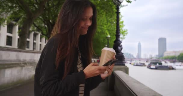 Londra Elinde Kahve Thames Nehrinin Kenarında Cep Telefonuyla Mesajlaşırken Gülümseyen — Stok video