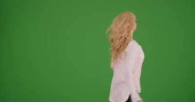 Güzel beyaz kadın yeşil ekranda kendi kendine dans edip gülüyor. Anahtar ya da birleşik olmak üzere yeşil ekranda.
