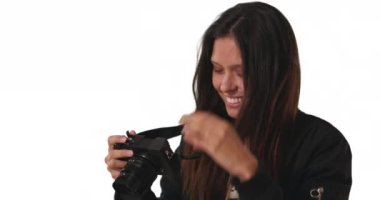 Bombacı ceketli hippi kızın beyaz arka planda DSR kamerasıyla fotoğraf çekişini yakın plan. Stüdyoda fotokopi çekmek için kamera merceği odaklayan yaratıcı bir kadın. 4k