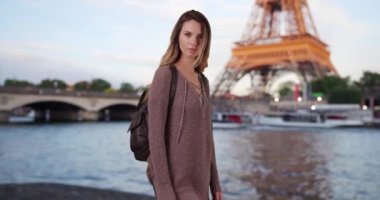 Gün batımında Seine 'de kameraya gülümseyen bir kadın. Sırt çantasıyla Eyfel Kulesi 'nin yanında duran gülümseyen bir turist. 4k