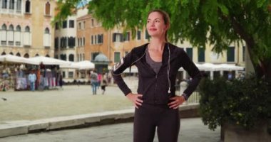 Venedik 'te bir portre için poz veren sağlıklı aktif kadın koşucu. Atletizmde kendine güveni tam bir kadın kameraya gülümsüyor. 4k