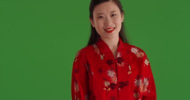 Gülümseyen neşeli Asyalı kadın geleneksel Çin tarzı takım elbise giyiyor ve yeşil ekranda izole edilmiş. Geleneksel Asya modasıyla yeşil krom anahtarın önünde duran mutlu Çinli kız. 4k