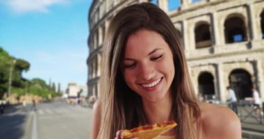 Roma Kolezyumu 'nun yanında kameraya gülümseyen mutlu bir kadının yakın çekimi. Kolezyum tarafından Roma 'da pizza dilimi yiyen çekici beyaz esmer. 4k