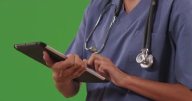 Yeşil ekrana notlar kaydetmek için tablet bilgisayar kullanan modern tıp doktorunun yakın çekimi. Doktorun notlarını yeşil ekrandaki taşınabilir tablet üzerinde okuyan profesyonel hemşireyi kapatın. 4k