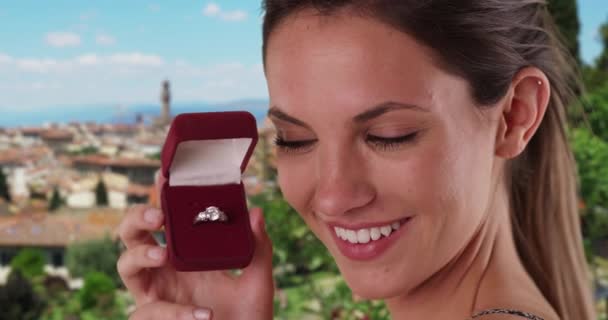 宝石箱でダイヤモンドリングを示す喜びの女性は 彼女の後ろのフィレンツェの街並みとカメラに イタリアのフィレンツェで婚約指輪を披露する幸せな千年の女の子 — ストック動画