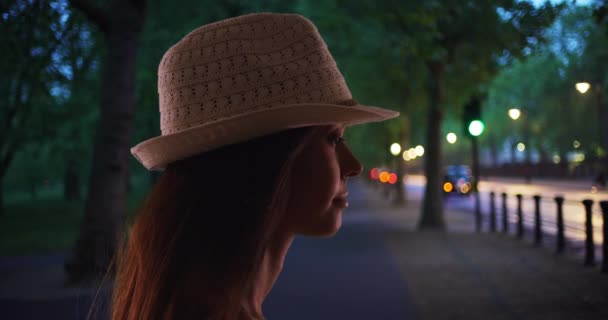 傍晚时分 穿着夏威夷帽的年轻女子的轮廓 晚上站在街上的女性面容阴沉的侧视图 — 图库视频影像