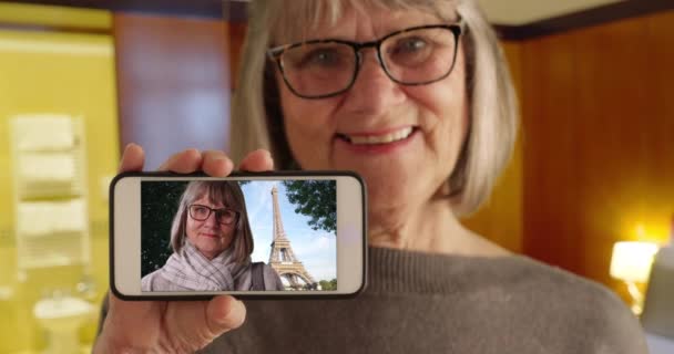 可爱的老妇人在巴黎通过艾菲尔铁塔向镜头展示自己的照片 成熟的白色女性展示了她在法国巴黎度假时的智能手机照片 — 图库视频影像