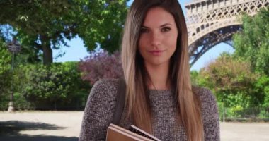 Eiffel Kulesi yakınlarında poz veren kendinden emin bir değişim öğrencisi. Paris 'te üniversitede ünlü bir kent simgesinin yanında duran zeki beyaz kadın öğrencilerin portresi. 4k