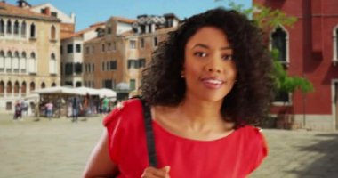 Mutlu genç siyah kadın kareye giriyor sonra Venedik 'te tatildeyken kameraya gülümsüyor ve el sallıyor. İtalya 'da tatil yapan Afrikalı Amerikalı turist kameraya gülümsüyor. 4k