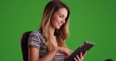 Yeşil ekranda tablet kullanan başarılı kadın milenyumu. Anahtar ya da birleşik olmak üzere yeşil ekranda.