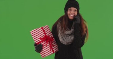 Kafkasyalı neşeli bir kadın, yeşil ekranda Noel hediyesiyle akıllı telefondan konuşuyor. Yeşil ekranda duran mutlu güzel kadın yeşil ekranda bayram hediyesiyle cep telefonuyla sohbet ediyor. 4k
