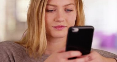 Güzel bir milenyum kızı cep telefonuyla mesaj yolluyor. Akıllı telefon cihazıyla internette gezinen güzel beyaz bir kadının yakın çekimi. 4k