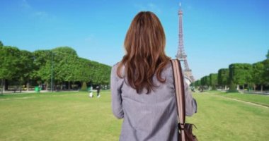 Eiffel Kulesi 'nin fotoğrafını çeken seyahat fotoğrafçısının arka görüntüsü. Paris 'te tarihi yerleri fotoğraflayan kadın turist. 4k