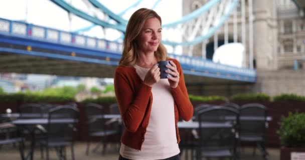 ロンドンの女性がコーヒーを飲んでいるカジュアルな肖像 外でコーヒーとリラックスして幸せと魅力的な女性 — ストック動画